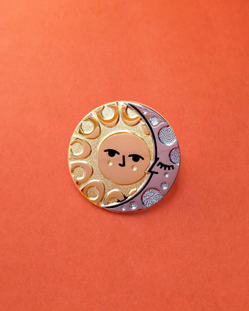 Illumine solar and lunar enamel pin seconds in gold and silver. With a classic sun face and sleeping moon.